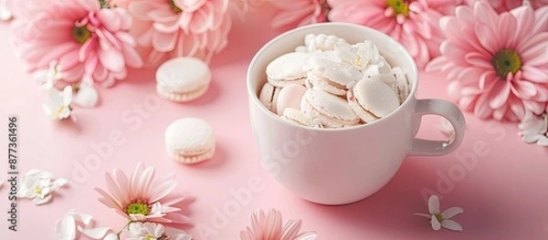 Fototapeta Delicate spring themed arrangement featuring a thoughtful gift for mothers daughters or any cherished woman a white cup filled with treats on a soft pink backdrop with room for text. Copy space image