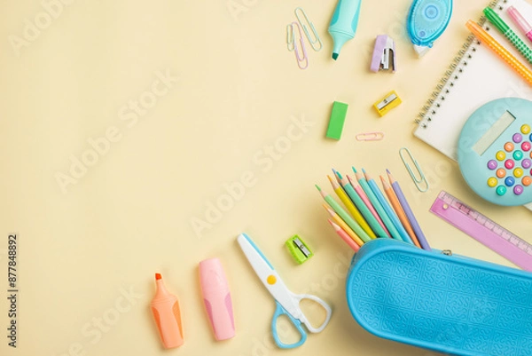 Obraz Back to school concept. Flat lay, top view colorful school supplies, blue pencil case, calculator, notepad on light yellow background.