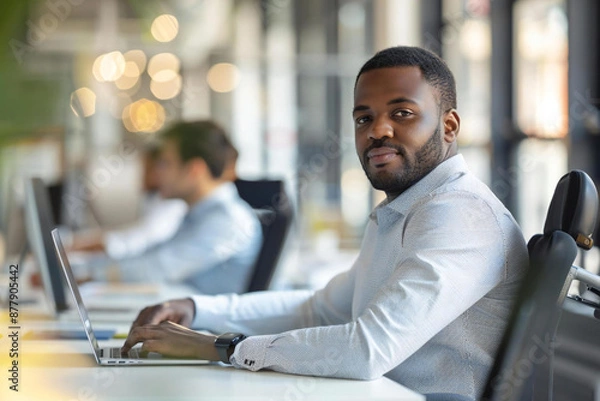 Obraz The photo captures a disabled African American male manager sitting with his colleagues at their office meeting, showcasing diversity and inclusion in the workplace. He is seen using a wheelchair.