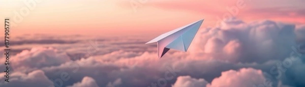 Fototapeta Paper airplane soaring through the clouds at sunset with a beautiful pinkish sky, symbolizing dreams and imagination.