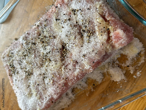 Fototapeta Homemade salted bacon with garlic and pepper in a glass container on a wooden surface.