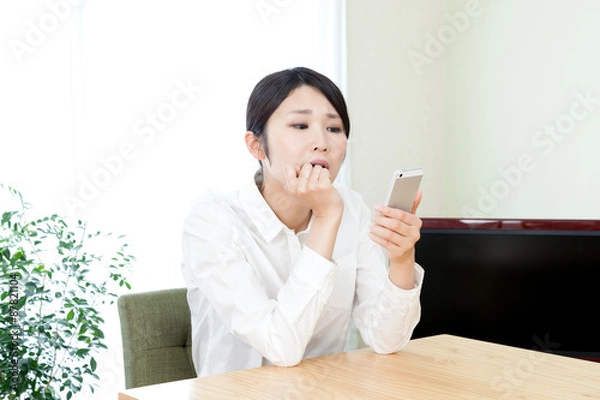 Fototapeta 女性　部屋　家　屋内　自宅　スマートフォン　モバイル　インターネット　悩む　トラブル　顎に手　頬杖