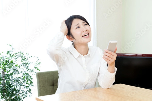 Fototapeta 女性　部屋　家　屋内　自宅　スマートフォン　モバイル　インターネット　悩む　トラブル　頭を抱える