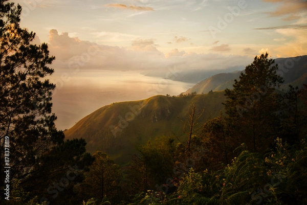 Obraz This captivating photo captures a golden sunrise over Lake Toba in Sumatra, Indonesia. The serene waters and lush hills create a tranquil scene, perfect for nature and travel enthusiasts seeking a bre
