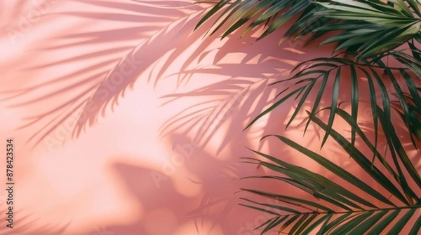 Fototapeta Palm tree leaves cast shadows on a pink background, creating a tropical and summery vibe.