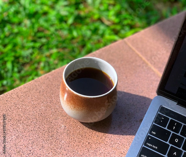 Obraz cup of coffee in the morning with blur grass background and laptop keyboard