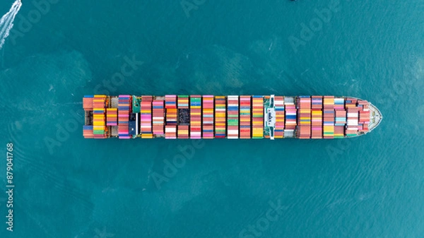Fototapeta Cargo container ship carrying container and running in the ocean near international container port customs shipyard sea port concept smart logistic service. transportation logistics trading..