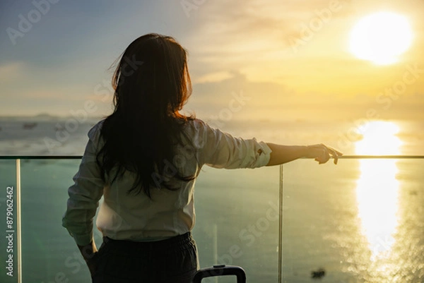 Obraz Attractive woman in beautiful beach hotel looking to beautiful view of a golden sky and the sun's rays shining on the sea, Big sun, enjoying freedom and life. Calmness, Relaxation.