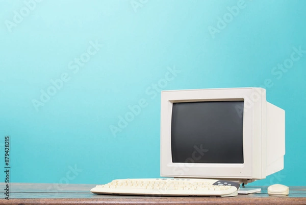 Obraz Retro desktop computer monitor, keyboard and mouse from circa 90s on oak wooden table front mint blue background. Vintage style filtered photo