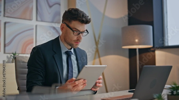 Fototapeta Serious specialist watching tablet comparing computer screen at office closeup