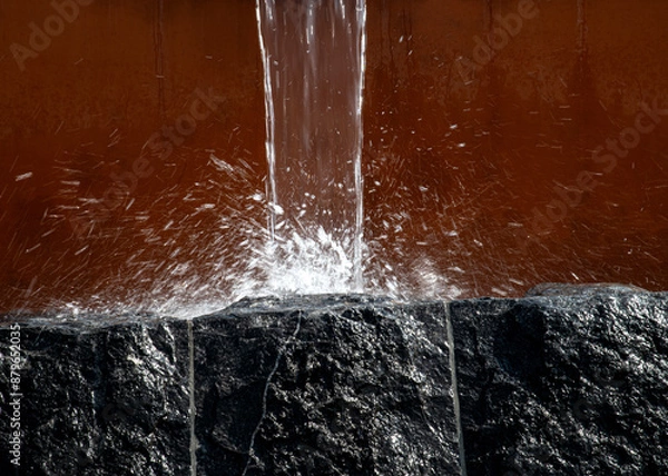 Obraz Water pours from a gutter and falls on a stone