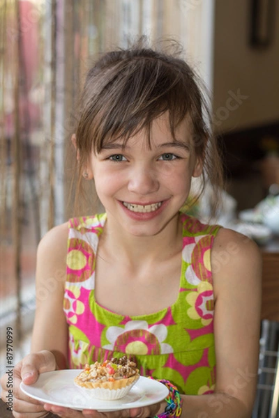 Fototapeta Girl in a cafe with a cake with nuts and candied fruits