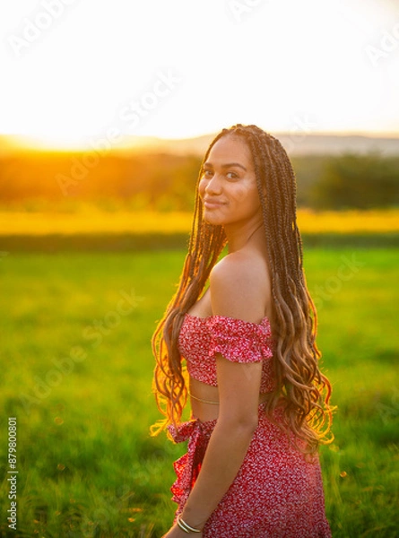 Fototapeta happy young black woman in a red dress on the wheat field in sunset light. future family concept