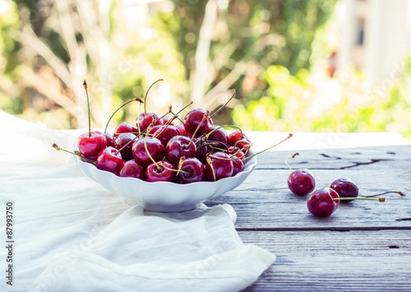 Fototapeta fresh red cherries in a plate, on a background of green garden,