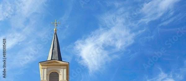 Fototapeta A steeple from a Christian church against a blue sky with a lot of copy space image available.