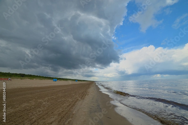 Fototapeta Beach scene with overcast sky, waves, nature, and travel keywords