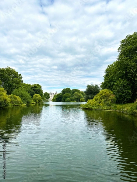 Fototapeta Beautiful lake surrounded by bushes and trees with a cloudy sky
