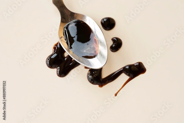 Fototapeta Balsamic vinegar from Modena on a spoon. An important ingredient in the sauce of Italian cuisine. Balsamic notes in perfumery, balsamic mood.  Warm sunlight, eco simple style. Earth tones 
