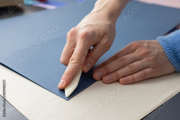 Fototapeta High-quality image of a person binding a book using traditional coptic stitch technique. DIY bookbinding, handcrafting, artisan book, handmade, coptic stitch, binding tools, creative, detailed process