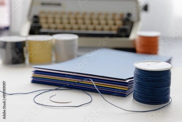 Fototapeta High-quality image of a person binding a book using traditional coptic stitch technique. DIY bookbinding, handcrafting, artisan book, handmade, coptic stitch, binding tools, creative, detailed process