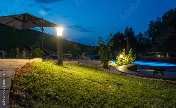 Fototapeta Dusk Capture of Luxurious Outdoor Pool Area with Modern LED Lighting Highlighting Path and Greenery