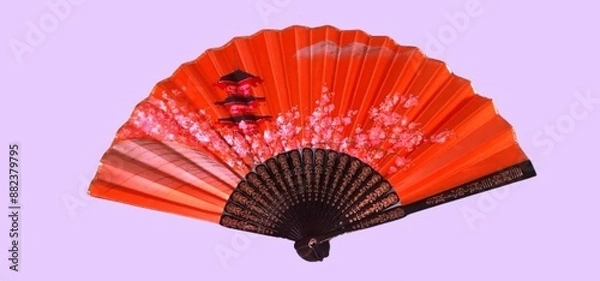 Fototapeta Bright orange Japanese hand fan featuring a cherry blossom and pagoda design, isolated on a pastel background