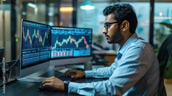 Fototapeta Financial securities traders, both male and female, working on desktop computers in a modern office. Handsome Indian accountant smiling happily while doing business financial accounting