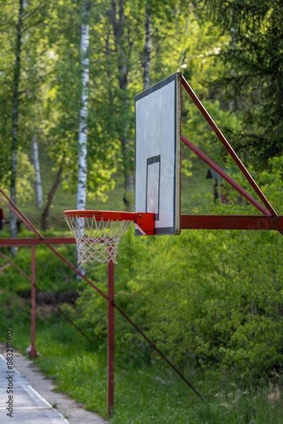 Fototapeta New basketball board with basket. Close up basketball hoop, board or basket. Close-up of net of basketball hoop in sunny day. Basketball rim in orange color bottom view on a white background.