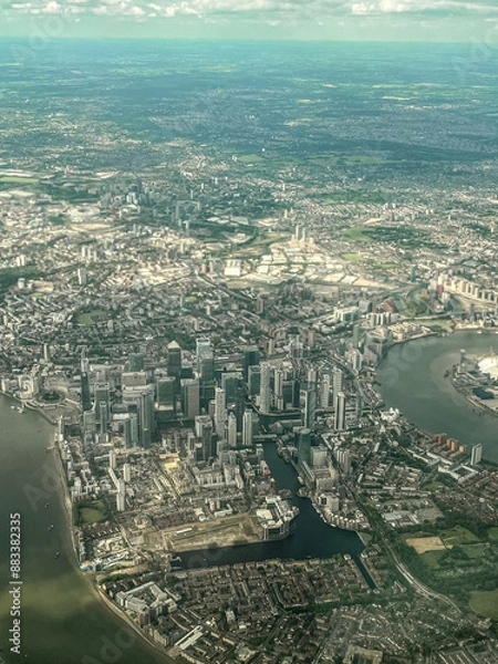Fototapeta Aerial view of London. View of the city centre of London from the window of the plane. Flying over the city with blue and grey landscapes. View of the river and skyscrapers.