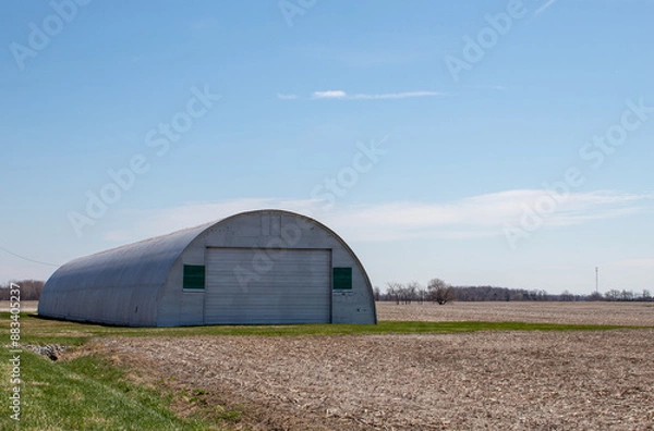 Fototapeta A half round barn in a corn field.