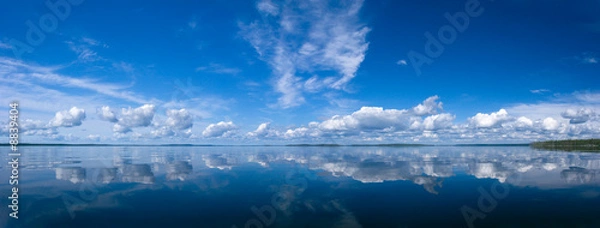 Fototapeta Blue bright summer sky with white clouds reflecting in lake