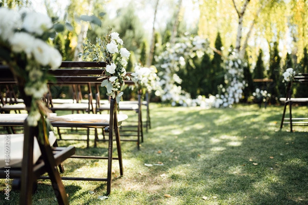 Fototapeta Wooden chairs decorated with flowers for an outdoor wedding ceremony