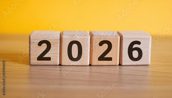 Fototapeta Wooden cubes with number 2026 on yellow backdrop. New year. Wood blocks. Close-up.