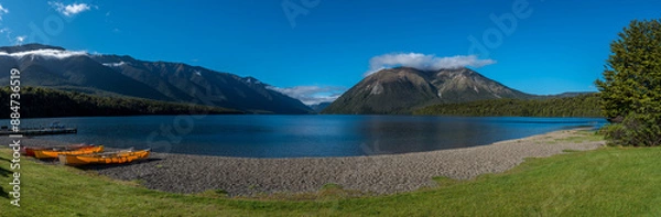 Fototapeta Wide panorama with canoes pulled up on the shore of Lake Rotoiti in Nelson Lakes National Park, New Zealand. Lake and mountains in the background.