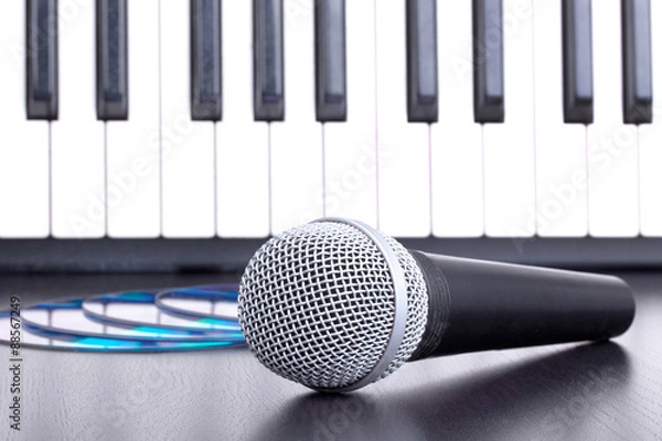 Fototapeta Microphone, cd disks and piano keyboard on black table