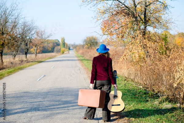 Fototapeta Lonely lady walking away with retro suitcase and giutar.