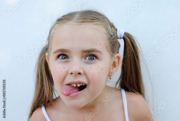 Obraz a mischievous, cheerful little girl with freckles rejoices and makes faces