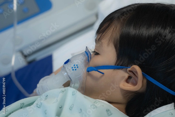 Fototapeta an Asian toddler boy has Cold or Flu or influenza or asthma or pneumonia disease and need nebulizations,Sick boy rest on patient bed in hospital and has inhalation therapy by the mask of inhaler.Sick 