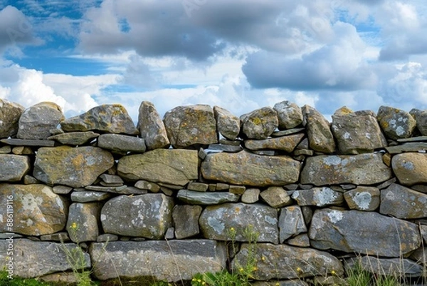 Fototapeta View of old dry stone wall under a cloudy sky.