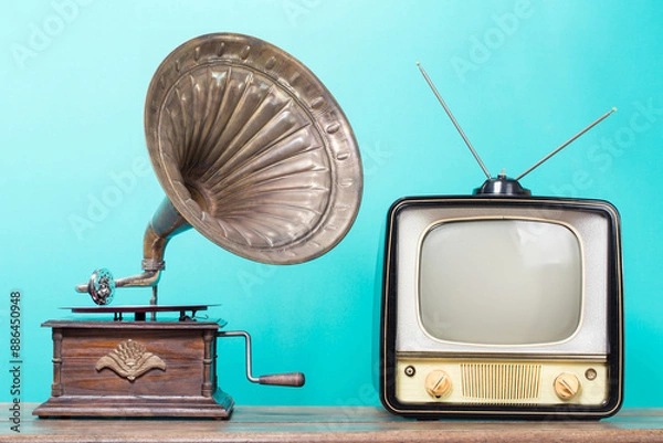 Obraz Retro TV and antique gramophone phonograph turntable with brass horn on old wooden table front mint blue background. Vintage style filtered photo