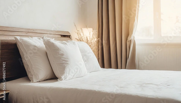 Fototapeta Clean Bedding sheets and pillow on natural wall room background. White bedding and pillow in hotel room. White pillows on empty bed.