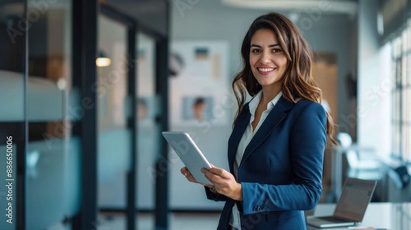 Fototapeta A businesswoman using a tablet and smiling in a modern office setting.