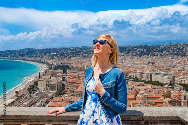 Fototapeta A woman enjoys a coastal city view on a sunny day, embracing the beauty and leisure of the moment. Nice, France.