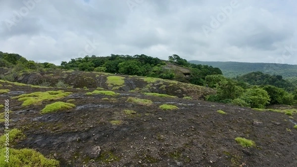 Fototapeta Green Patches on Rocky Terrain Under Cloudy Sky