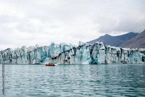 Fototapeta A boat next to a glacier cliff in jokulsarlon in Iceland