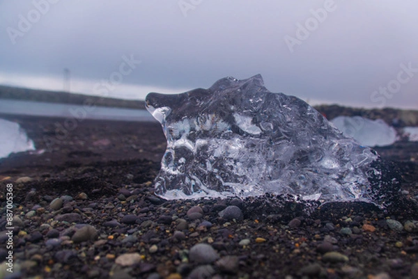 Fototapeta stranded icebergs on a dark pebbly beach in jökulsárlón in iceland