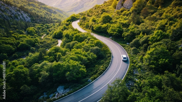 Fototapeta Car Driving on a Curvy Mountain Road Surrounded by Lush Green Forest