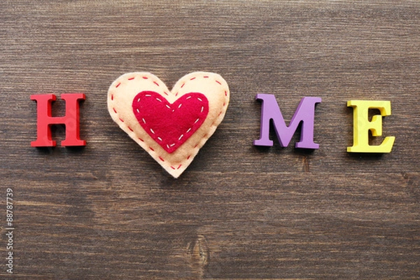 Fototapeta Decorative letters forming word HOME with heart on wooden background