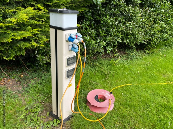 Fototapeta Electric hook-up cables have been plugged into a campsite electrical supply point.An extension lead can be seen on the ground.Hook Up.Motorhoming.