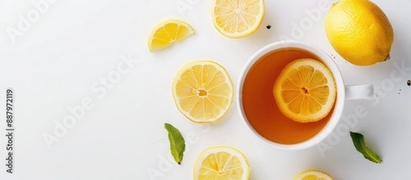 Fototapeta Ginger tea with lemon and honey in a cup garnished with fresh lemon slices on a white background providing copy space image